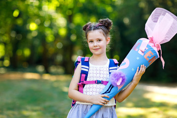 Happy little kid girl with backpack or satchel and big school bag or cone traditional in Germany...