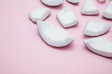 Tropical summer coconut pieces on a pastel pink background.