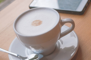 
a cup of coffee with foam and a smartphone on the table