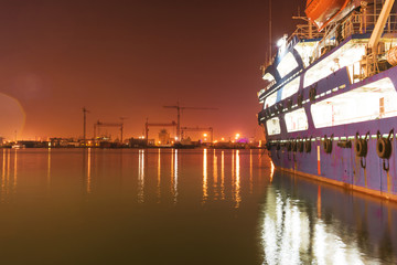 Industrial ships moored in the harbor, city background, at night