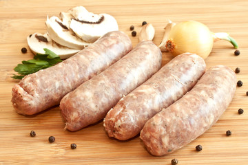 Uncooked sausages with vegetables on the chopping board