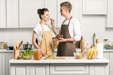 boyfriend feeding girlfriend with strawberry in kitchen