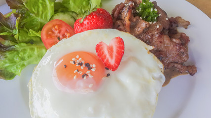 Fried egg with Strawberry  pork steak and salad meat dinner in dish on wooden background