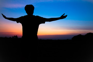 Blurr. Silhouette,Asian young man in hat hiking standing open arm happy at mountain peak above sunset ligth, Hiker outdoor.