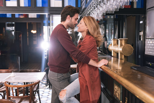 Tell me more. Glad pretty man posing in profile while woman sitting