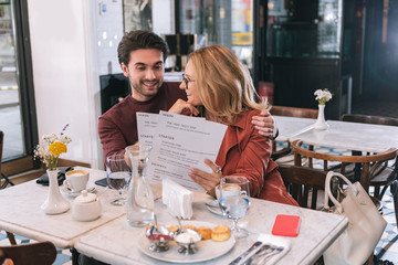 Fancy restaurant. Joyful jolly couple selecting meal and sitting at table