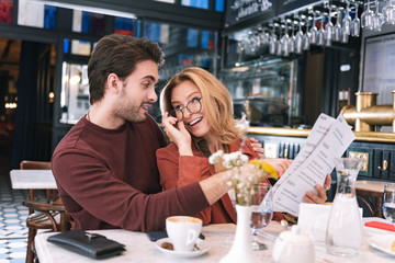 Wine card. Pretty positive couple choosing meal and looking at each other