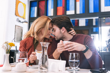 Time for coffee. Low angle of pensive sincere couple drinking coffee and cuddling