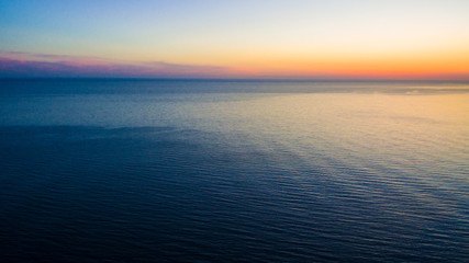 Drone view of a wide sea surface and the horizon at sunset
