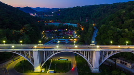 Drone view of the illuminated Matsesta viaduct on the background of mountainsides with dense forest...