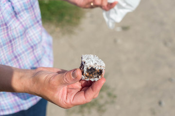 Women holding a piece of chocolate with coconut powder on natural light.