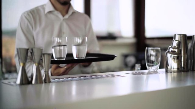 Waiter pours into a glass of cold water, puts on a tray and walking to a customer in hotel or restaurant, who is tormented by thirst on a hot summer day. Rome, Italy. 4K (UHD) medium video.