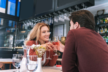 Humble engagement. Low angle of nice satisfied couple drinking wine and having date at restaurant