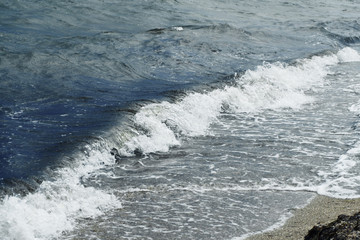 Small waves with foam at the time of storm beginning in the evening on the shore of the dark sea on the beach of the sea resort
