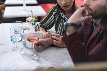 Serious conversation. Close up of transparent glasses standing on table and female hands touching male hand