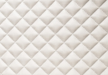 leather background. A closed up details of a beige leather paded upholstery pattern texture.
