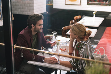Time together. Cheerful sincere couple holding hands and visiting restaurant