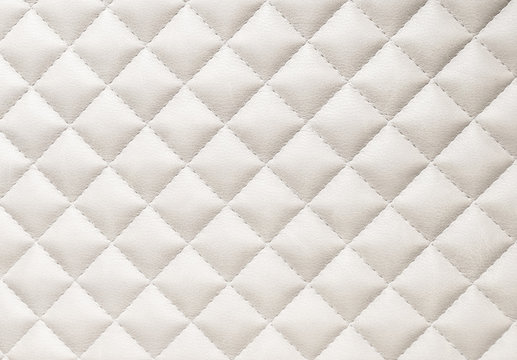 leather background. A closed up details of a beige leather paded upholstery pattern texture.