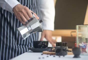 barista man holding cup of hot coffee to drink in cafeteria with copy space for text on advertisement board