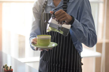 barista man holding cup of hot coffee to drink in cafeteria with copy space for text on advertisement board
