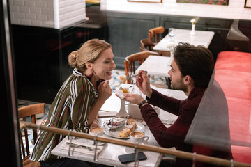 Delicious starter. Top view of cheerful mature woman opening mouth while man carrying fork