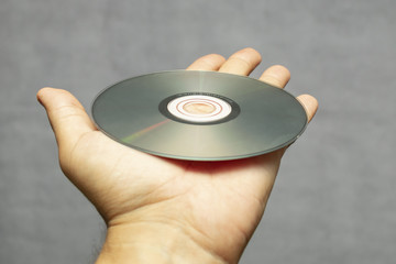 compact disc for audio on the palm, close-up on a gray blank background