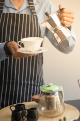 barista man holding cup of hot coffee to drink in cafeteria with copy space for text on advertisement board
