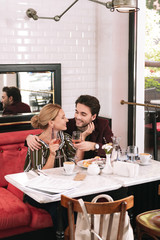 True love. Merry satisfied couple sitting at restaurant and flirting