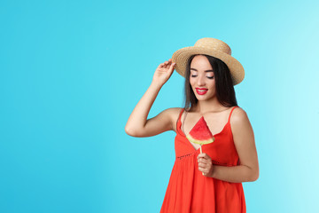 Beautiful young woman posing with watermelon on color background