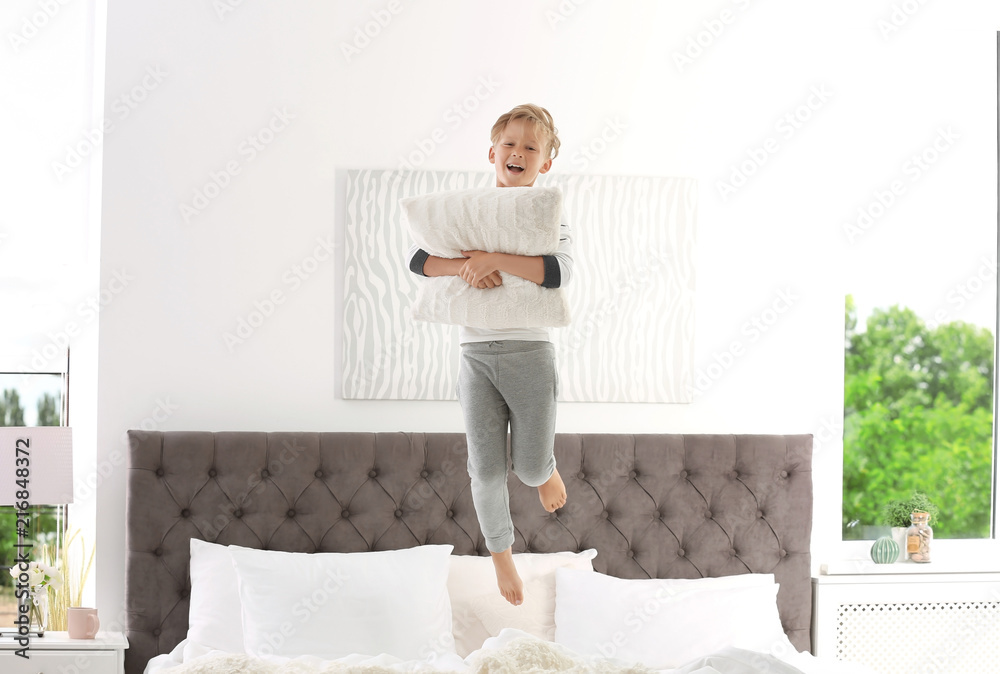 Sticker cute little boy with pillow jumping on bed at home