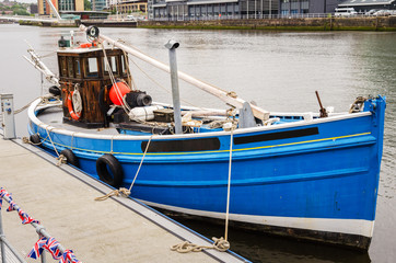 Fototapeta na wymiar Blue Fishing Boat Moored to a Jetty on a Rainy Day. Newcastle upon Tyne, England, UK.