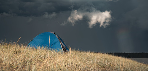 A camp tent on a hill. Thundercloud in the background