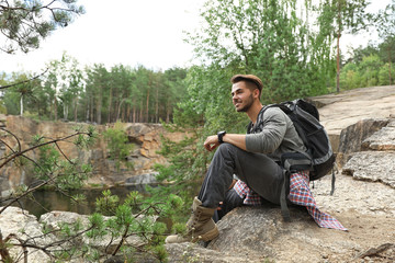 Young man on rocky mountain near forest. Camping season