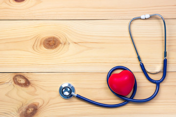 Stethoscope and red heart shape on wooden background, top view design