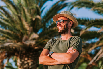 Young man standing by the palm trees looking at sun