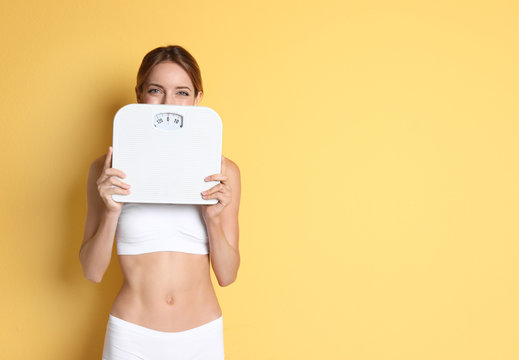 Happy Slim Woman Satisfied With Her Diet Results Holding Bathroom Scales On Color Background