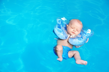 Fototapeta na wymiar Cute little baby with inflatable neck ring in swimming pool on sunny day, outdoors