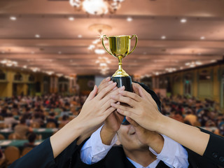 Businessman and businesswomen raise the golden trophy as the winner. Gold trophy as a leadership. Business successful. Team cooperate win the golden prize.