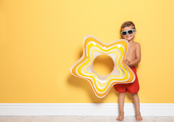Cute little boy with bright star shaped inflatable ring near color wall