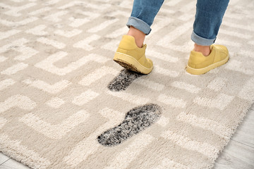 Person in dirty shoes leaving muddy footprints on carpet