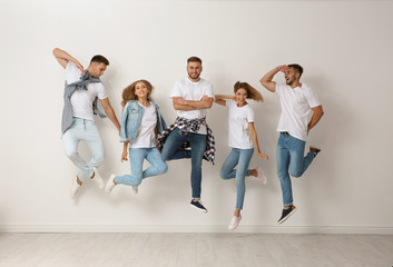 Obraz premium Group of young people in jeans jumping near light wall