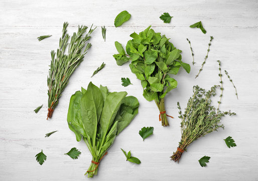Flat lay composition with fresh green herbs on white wooden background