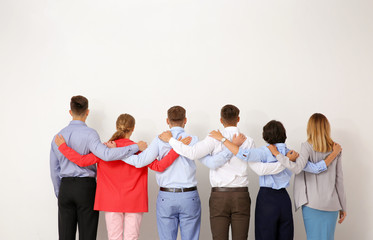 Fototapeta premium Group of young people hugging each other on light background. Teamwork concept