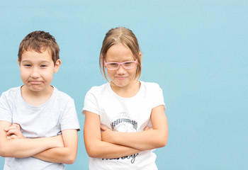 Kids brother and sister twins 8 years old standing with funny faces on blue background