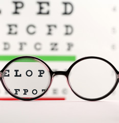 Glasses on table against eye chart, view through lenses