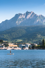Fototapeta na wymiar man are doing yoga on a stand up paddle board SUP on a beautiful Lake Lucerne, Pilatus mountain the summer season, boats and ships, travel and vacation to Europe concept, Luzern, Switzerland