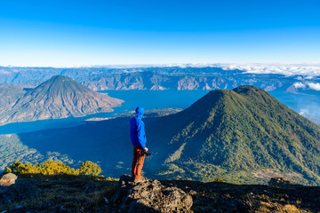Hiker with panorama view of Lake Atitlan and volcano San Pedro and Toliman early in the morning...