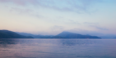 Sunrise in bay of sea. Morning haze, beautiful view on mountains and sea.