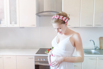 pregnant woman in the kitchen in a white dress.