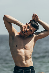 Fototapeta na wymiar handsome shirtless man stretching neck before workout in front of sea